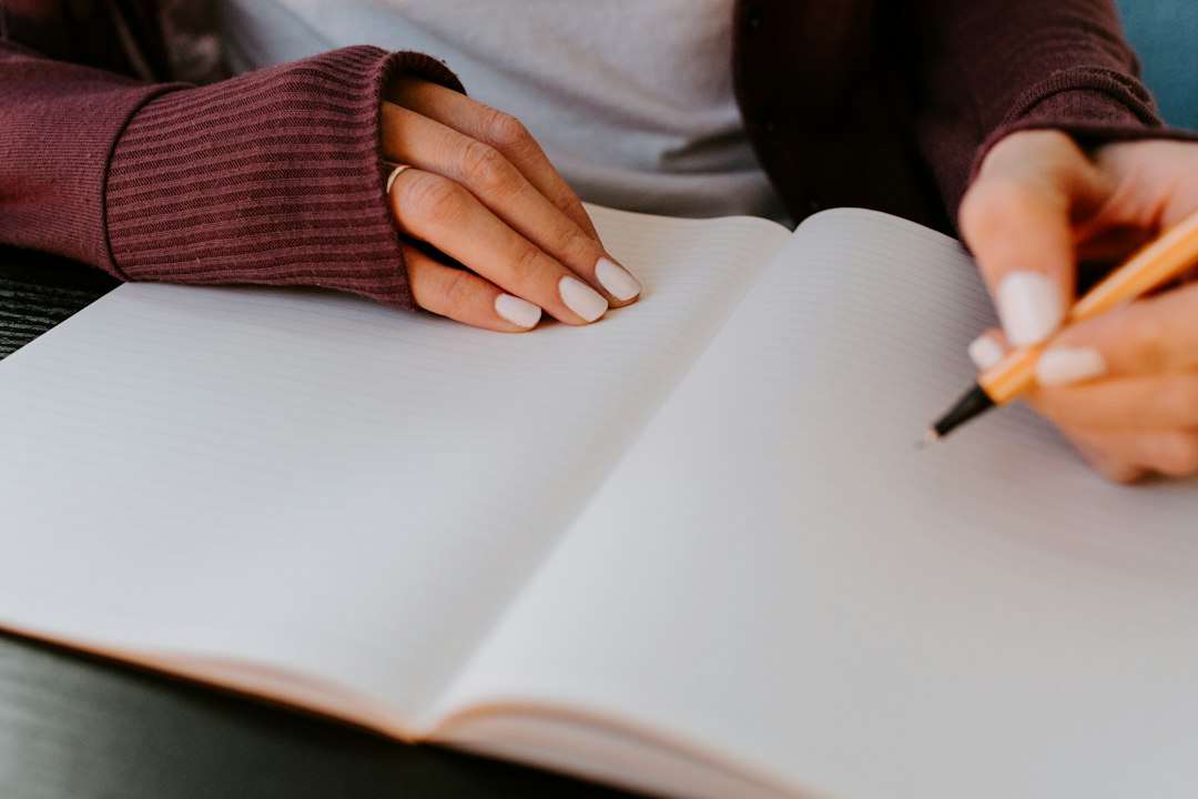 Hands writing in a journal at a calm home workspace